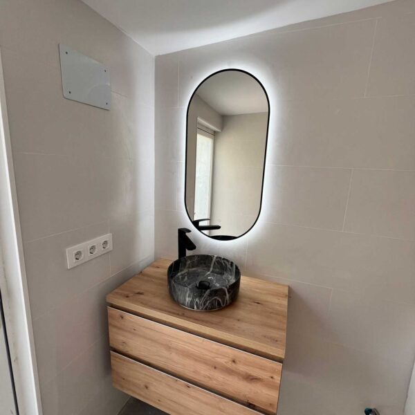 Mueble de baño suspendido con lavabo oscuro y espejo ovalado con luz LED