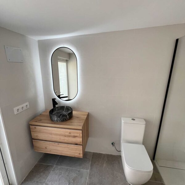 Mueble de baño suspendido con lavabo oscuro y espejo ovalado con luz LED