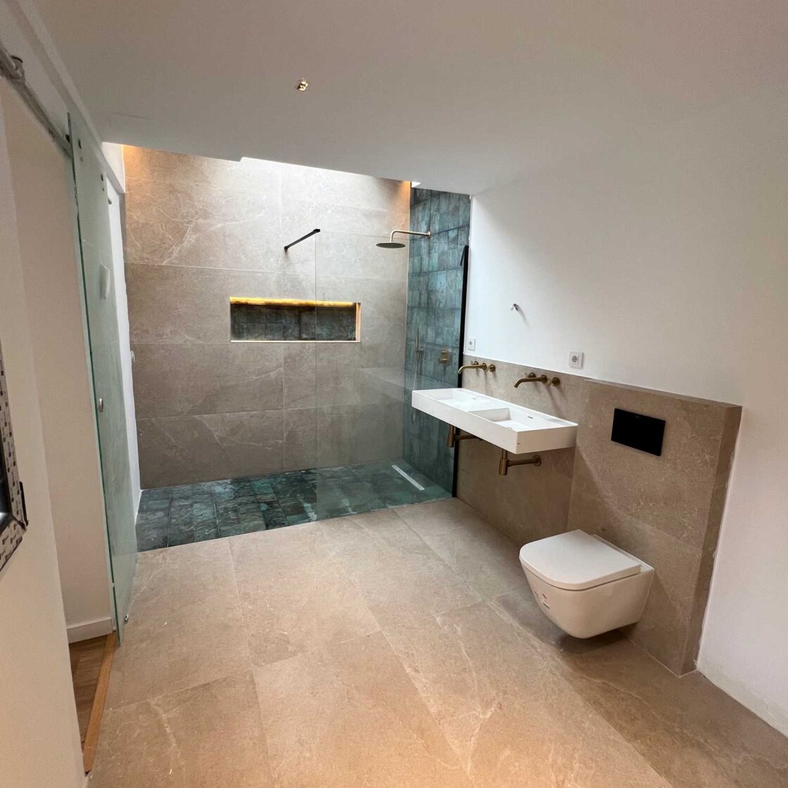 Baño reformado con mueble suspendido, lavabo de piedra y sanitario blanco
