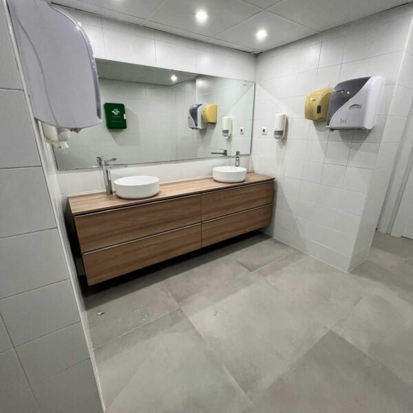 Lavabo sobre mueble de madera con espejo retroiluminado en baño reformado