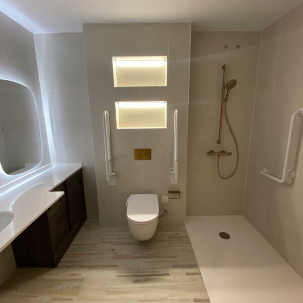 Baño amplio con ducha abierta, nicho iluminado y revestimiento cerámico