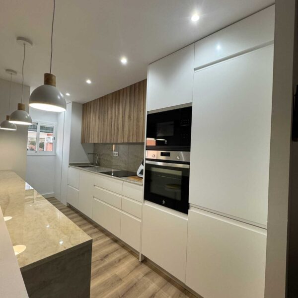 Cocina abierta con isla, iluminación colgante y electrodomésticos integrados