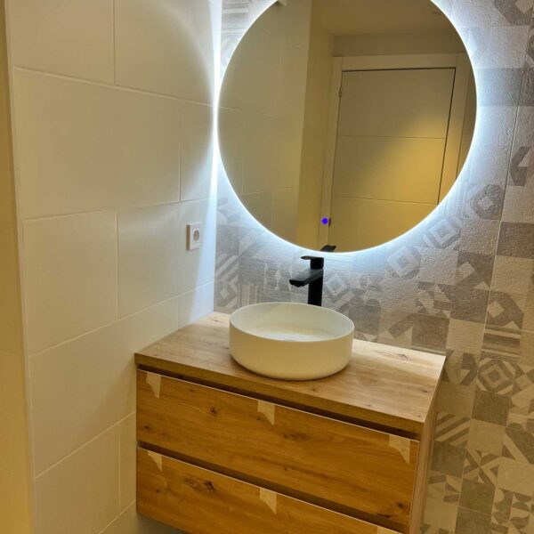 Lavabo sobre mueble de madera con espejo retroiluminado en baño reformado