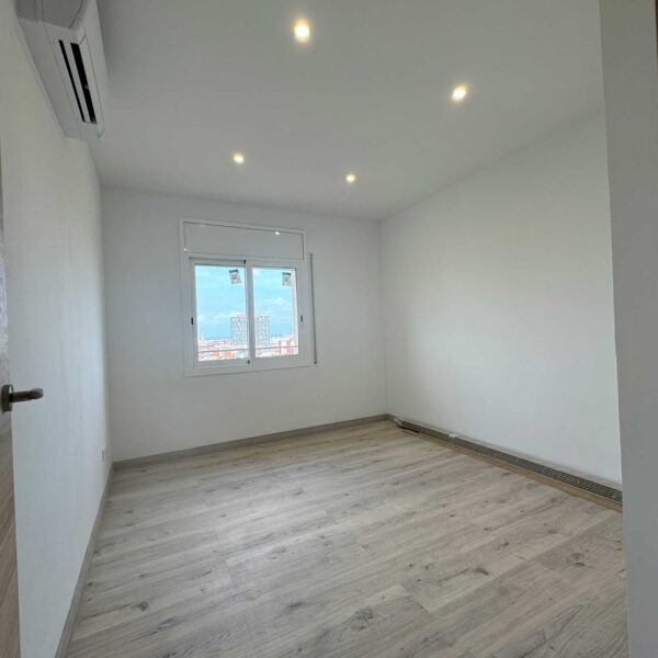 Habitación reformada con suelo laminado, paredes blancas y ventana exterior